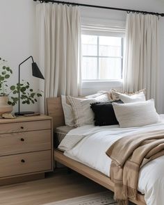 a bed with white sheets and pillows next to a window