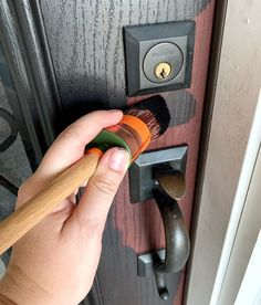 a person is holding a brush and painting the door handle on a wooden door knob