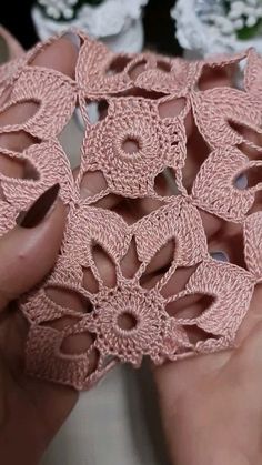 someone is holding some pink crocheted doily in their hands and they are working on something