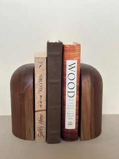 three books are stacked on top of each other in front of a wooden stand with two bookends