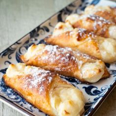 several pastries are on a blue and white plate with black design around the edges