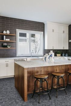 a kitchen with two stools next to an island in the middle of the room