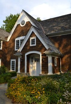 an image of a small house with flowers in the front yard and on the side