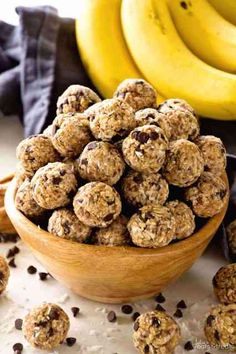 a wooden bowl filled with oatmeal chocolate chip energy bites next to bananas