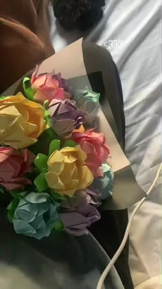 a bouquet of colorful paper flowers sitting on top of a bed