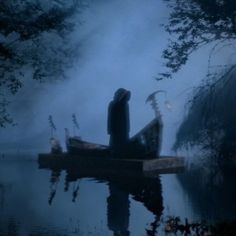 a boat floating on top of a body of water next to trees and foggy sky