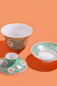 three bowls and two plates on an orange background