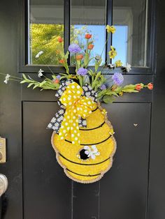 a yellow bee door hanger with flowers in it