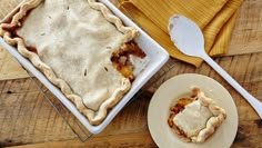 a pie sitting on top of a wooden table next to a plate with a fork