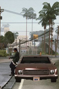 a man standing next to a brown car on a city street with palm trees in the background