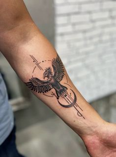 a man with a tattoo on his arm holding an arrow and bird in the middle