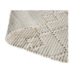 a white knitted blanket on top of a white flooring mat with holes in the middle