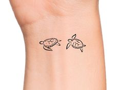 a small tattoo on the wrist of a woman's arm, with two turtles