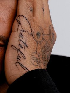 a man holding his hand to his face with the word faith tattooed on it's wrist