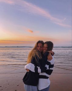 two women hugging each other on the beach