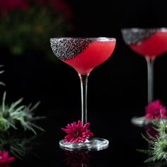 two wine glasses filled with red liquid and garnished with black glitter