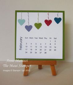 a calendar card with hearts hanging from it's sides on a wooden easel