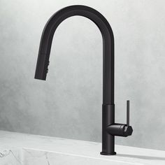 a black kitchen faucet on a white countertop next to a gray wall