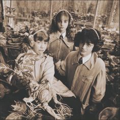 an old black and white photo of three children with vegetables in their hands, standing next to each other