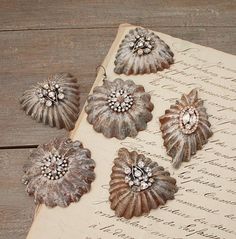 an old book with five antique flower brooches on it's cover, sitting on a wooden table