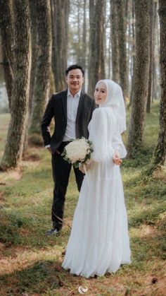 a bride and groom standing in the woods