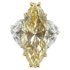 a fancy yellow diamond ring with two white diamonds on the band and an oval cut center stone