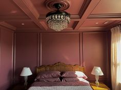 a bed sitting under a chandelier in a bedroom