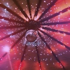 the inside of an umbrella is lit up with white lights and stars on pink background