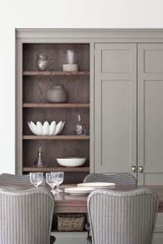 a dining room table with two chairs and a bookcase in front of it that is built into the wall