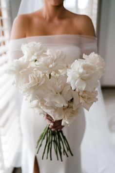 a bride holding a bouquet of white flowers