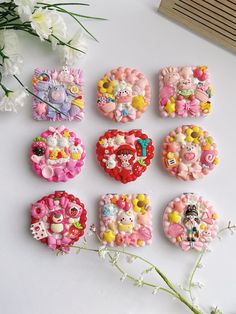 there are many different types of brooches on this white surface with flowers in the foreground