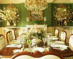 a formal dining room with green walls and chandelier above the table set for four