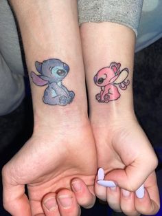 two people holding hands with tattoos on their arms and one has a small cartoon character on the wrist