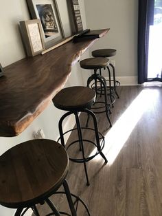 a row of stools sitting on top of a wooden counter next to a window