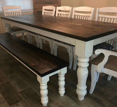 a dining room table with white chairs and a bench