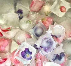 some ice cubes with flowers in them are sitting in a metal bowl filled with water