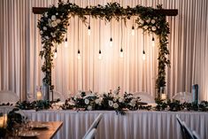 the table is set up with flowers and greenery for an elegant wedding reception at the four corners of the room