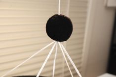 a close up of a black and white object hanging from strings on a window sill