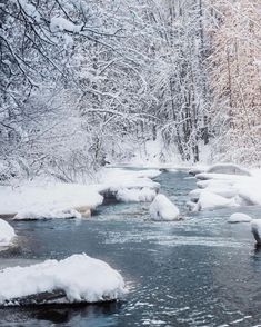 a river with snow covered rocks and trees in the background