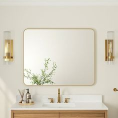 a bathroom vanity with a large mirror above it and two gold faucets next to it