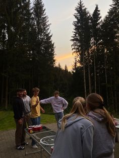 a group of young people standing next to each other in front of some tall trees