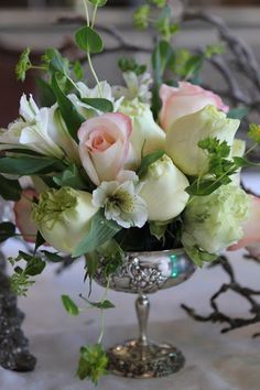 a vase filled with white and pink flowers on top of a table covered in greenery