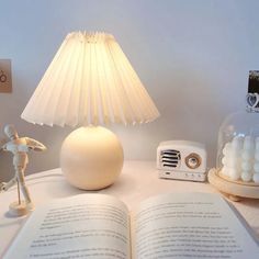 an open book sitting on top of a table next to a lamp and a radio