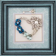 a blue frame holds a beaded bracelet and broochet in the shape of a heart