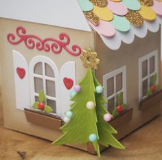 a paper house with a christmas tree in the front