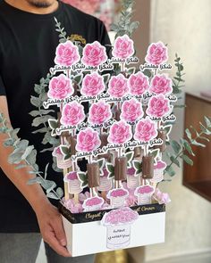 a man holding a bouquet of pink roses in front of a card board with stickers on it