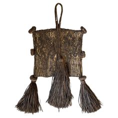 an old woven bag with tassels hanging from the side on a white background