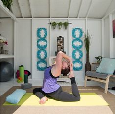 a woman is doing yoga in her living room while sitting on the floor and stretching