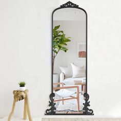 a mirror sitting on top of a wooden table next to a white chair and potted plant