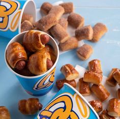 two cups filled with doughnuts sitting on top of a blue table next to donuts